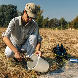 Agronomist collecting soil samples while crouching on field