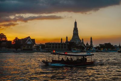 View of temple by building against sky during sunset