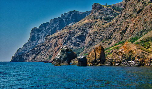 Rock formations by sea against blue sky