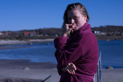 Young man using mobile phone at beach against sky