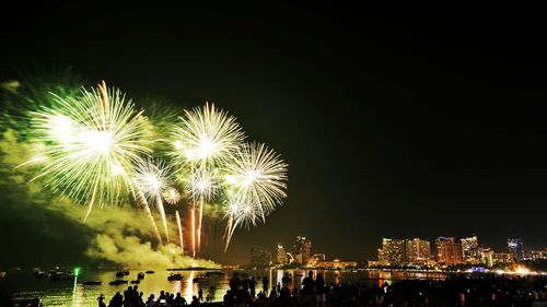 Firework display over river against sky at night