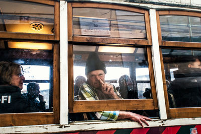 Portrait of young man looking through window