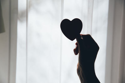 Midsection of woman holding heart shape window