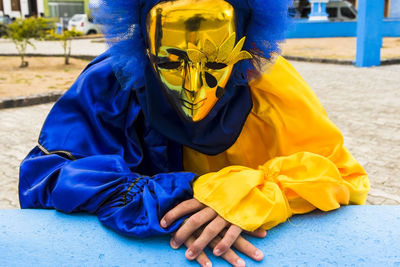 Person seated wearing carnival mask