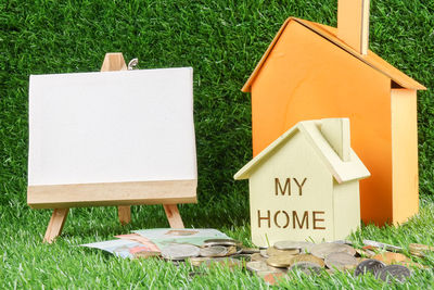 Close-up of model homes with canvas and currency on grassy field