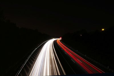 Light trails on road against sky at night