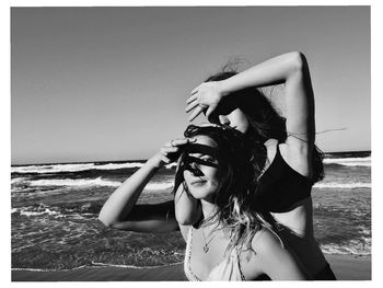 Woman wearing sunglasses at beach against clear sky