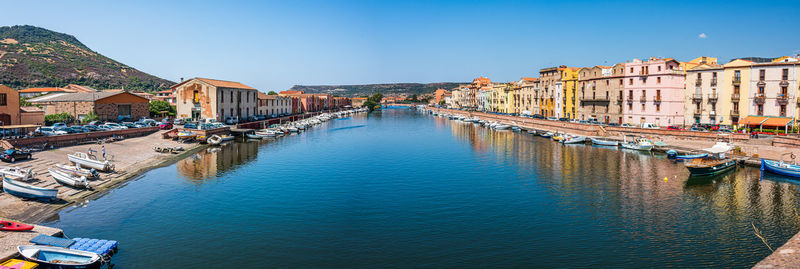 Canal amidst buildings in city against clear blue sky