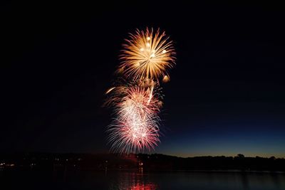 Firework display over river against sky at night