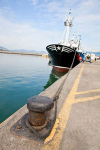 Boat moored at harbor against sky