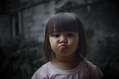 Portrait of cute girl puckering lips against wall