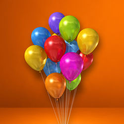 Close-up of multi colored balloons against orange background