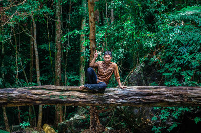 Full length of couple sitting on land in forest