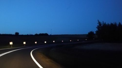 Empty road against clear blue sky at dusk