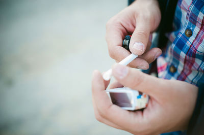Close-up of man hand holding cigarette and lighter