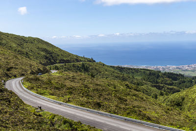 Scenic view of mountain road by sea against sky