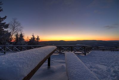 Snow covered trees against sky at sunset