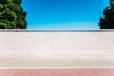 Wall by sea against clear blue sky