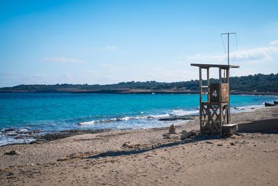 Lifeguard hut on beach against blue sky