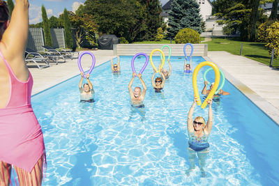 Group of seniors with trainer doing water gymnastics in pool