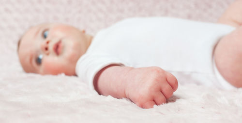 Close-up of cute baby girl lying on bed