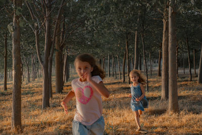Girl chasing sister while running in forest