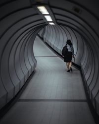Rear view of woman walking in tunnel