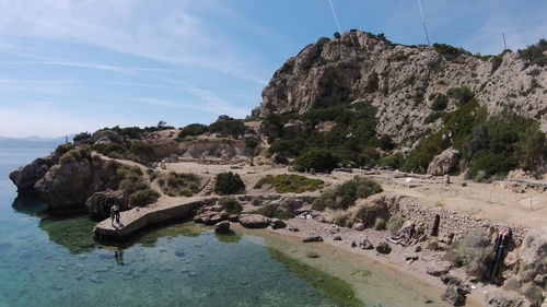 Scenic view of rock formation by sea against sky during sunny day