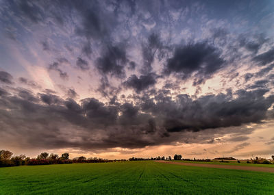 Scenic view of agricultural field against dramatic sky