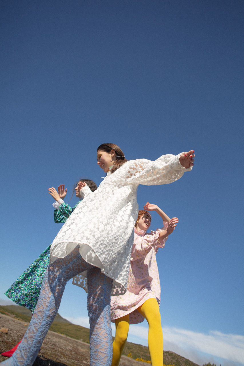 sky, blue, clear sky, two people, togetherness, lifestyles, three quarter length, copy space, low angle view, casual clothing, real people, leisure activity, people, happiness, young adult, bonding, emotion, day, nature, standing, positive emotion