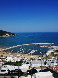 High angle view of town by sea against clear blue sky