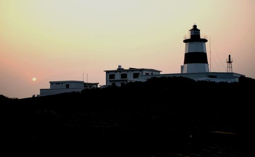 Silhouette of lighthouse against sky at dusk