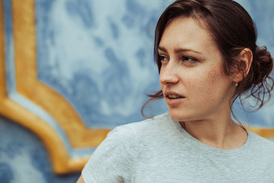 Headshot of young woman with freckles looking unpleasantly surprised