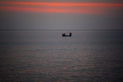 Silhouette boat in sea against sky during sunset