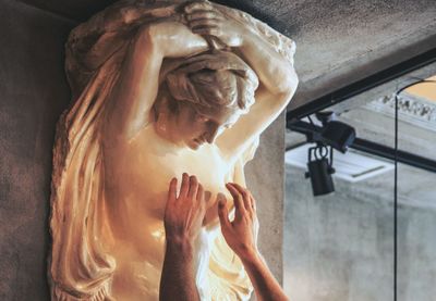 Cropped hands of man touching female statue breast