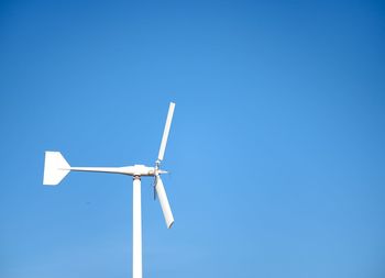 Low angle view of windmill against clear blue sky