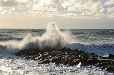 Waves splashing on shore against sky