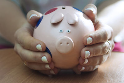 Close-up of hands holding piggy bank on table