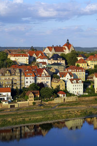 Houses by lake in town against sky