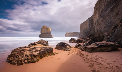 Rock formations on beach against sky