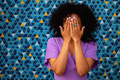 Woman covering face against wall