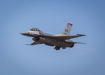 Low angle view of airplane flying against clear blue sky