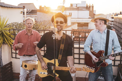 Musicians playing music on building terrace during sunset