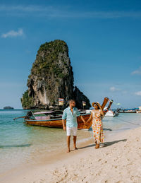 Rear view of woman standing at beach against sky