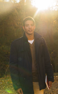 Portrait of young man standing against trees