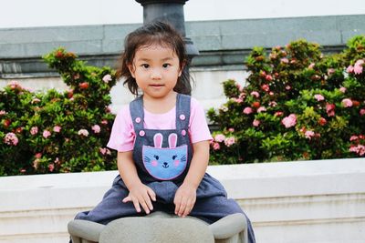 Portrait of girl sitting on elephant statue in park