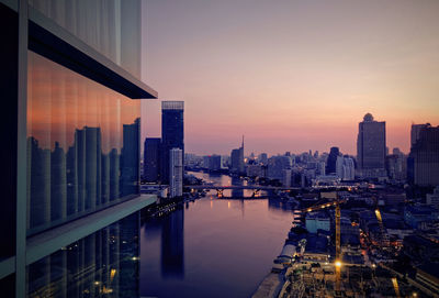 River by buildings against sky during sunset