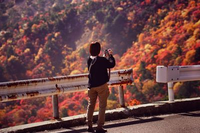 Woman photographing through camera against mountains