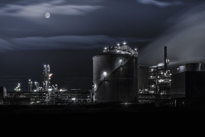 Illuminated factory against sky at night