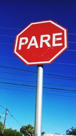 Low angle view of road sign against clear blue sky